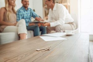A family discussing housing options at a dining table with floor plans and documents spread out.